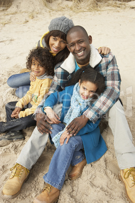 Family Sitting On Winter Beach