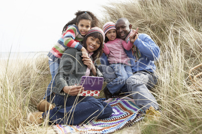 Family Sitting In Dunes Enjoying Picnic On Winter Beach