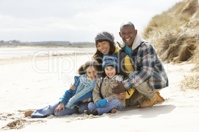 Family Sitting On Winter Beach