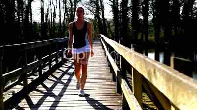 Frau joggt über Holzbrücke