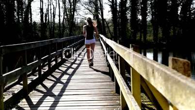 Frau joggt über Holzbrücke (von hinten)