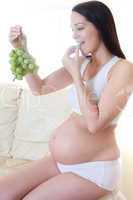 pregnant brunette woman eating grapes