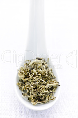 Dry white tea leaves in a spoon