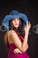 Pretty young smiling girl in cap on dark background