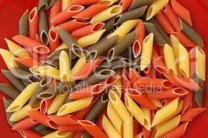 penne tricolore pasta on red background