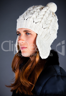 Portrait of the young girl in a winter cap on the dark