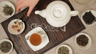 Woman adds brown sugar in cup of tea
