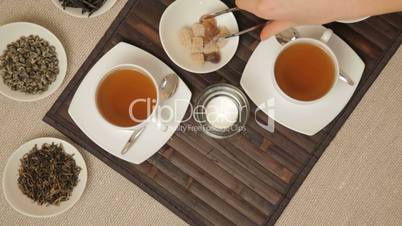 Woman adds brown sugar in cups of tea