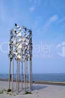 Vogelskulptur mit Amsel am Strand vor blauem Himmel