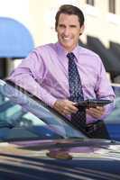 Businessman Leaning on Car with Tablet Computer