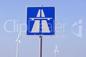 Autobahnschild und Windkraftanlagen