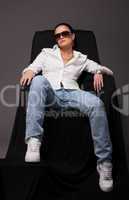 Young girl like tomboy sit on black chair