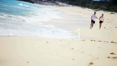 Healthy Young Couple Jogging Along the  Beach