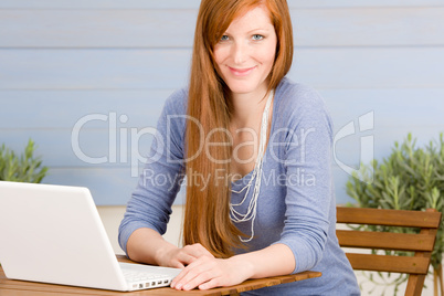 Summer terrace redhead woman with laptop