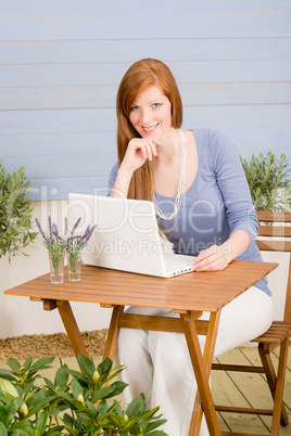 Summer terrace redhead woman with laptop