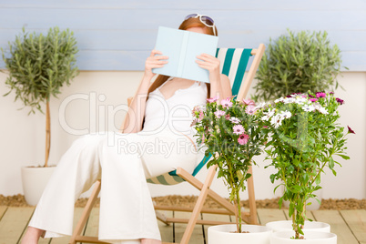 Summer terrace red hair woman read in deckchair