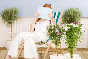 Summer terrace red hair woman read in deckchair