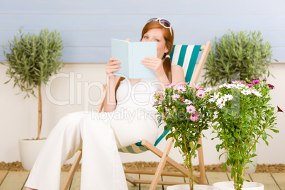 Summer terrace red hair woman read in deckchair