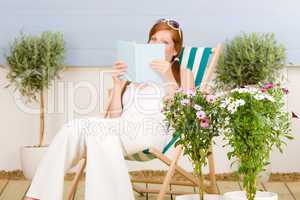Summer terrace red hair woman read in deckchair