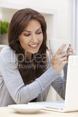 Woman Using Laptop Computer At Home Drinking Tea or Coffee