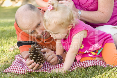 Father and Daughter Talk about Pine Cone in Park