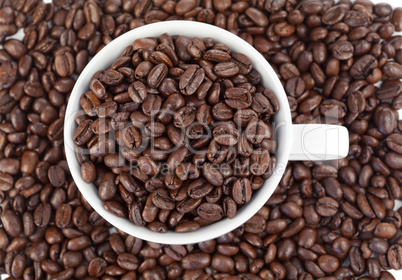 Small white cup of coffee full of coffee beans