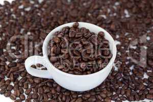 Small white cup of coffee with coffee beans