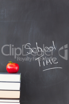 Stack of books with a red apple and a blackboard with "school ti