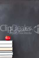 Stack of books with a red apple and a blackboard with "education