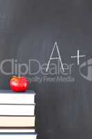 Stack of books with a red apple and a blackboard with "A+" writt