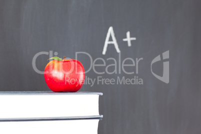 Stack of books with a red apple and a  blackboard with "A+" writ