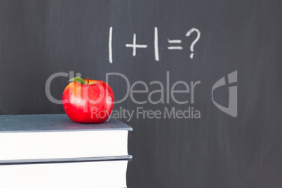 Stack of books with a red apple and a  blackboard with "1+1=?" w
