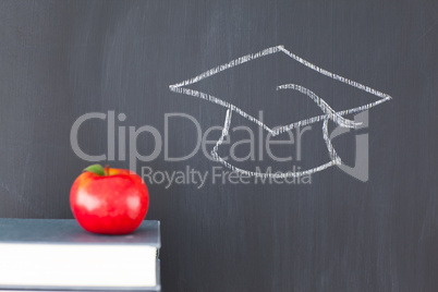 Stack of books with a red apple and a blackboard with a graduati