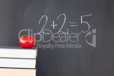 Stack of books with a red apple and a  blackboard with "2+2=5" w