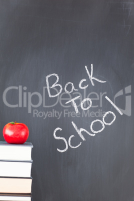 Stack of books with a red apple and a blackboard with "back to s