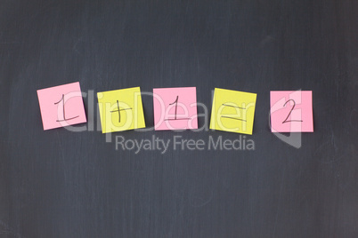 Pink and yellow sticky notes in a row on a blackboard