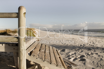 Hölzerner Steg an weitem Sandstrand mit Meer und blauem Himmel