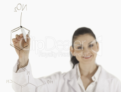 Smiling scientist writing a formula on a white board
