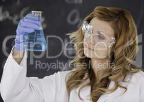 Beautiful female scientist looking at a flask