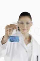 Female scientist with safety glasses holding a blue flask
