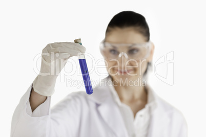 Female scientist looking at a blue test tube