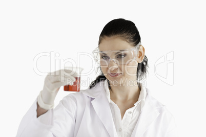 Dark-haired scientist looking at a red beaker