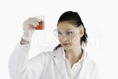 Dark-haired woman looking at a red beaker