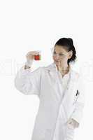 Scientist woman looking at a red beaker
