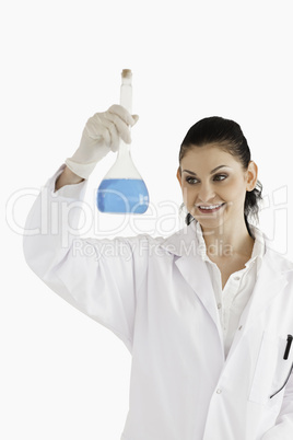 Dark-haired smiling scientist looking at a flask