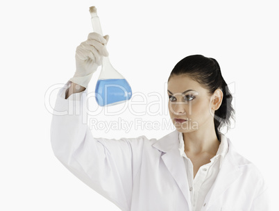 Dark-haired female scientist looking at a flask