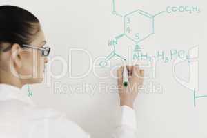 Dark-haired scientist woman writing a formula on a white board