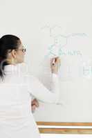 Scientist writing a formula on a chalkboard