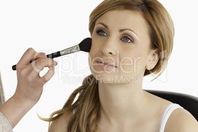 Make-up artist applying make up to a cute blond-haired woman