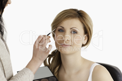 Make-up artist applying make up to a blond-haired woman